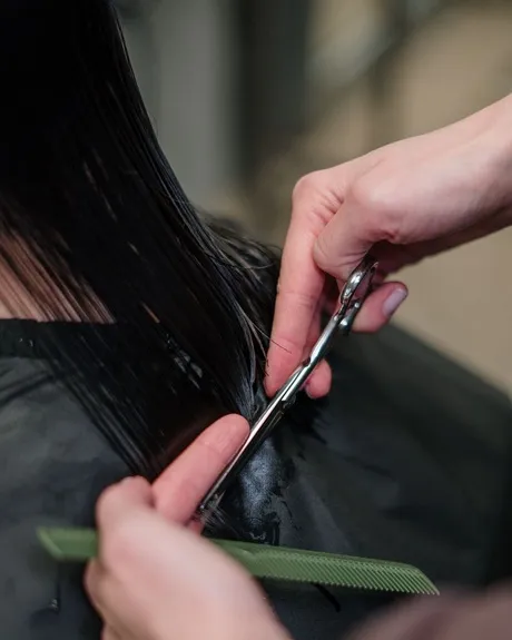 Une coupe en cours, ciseaux et peigne sur cheveux foncés